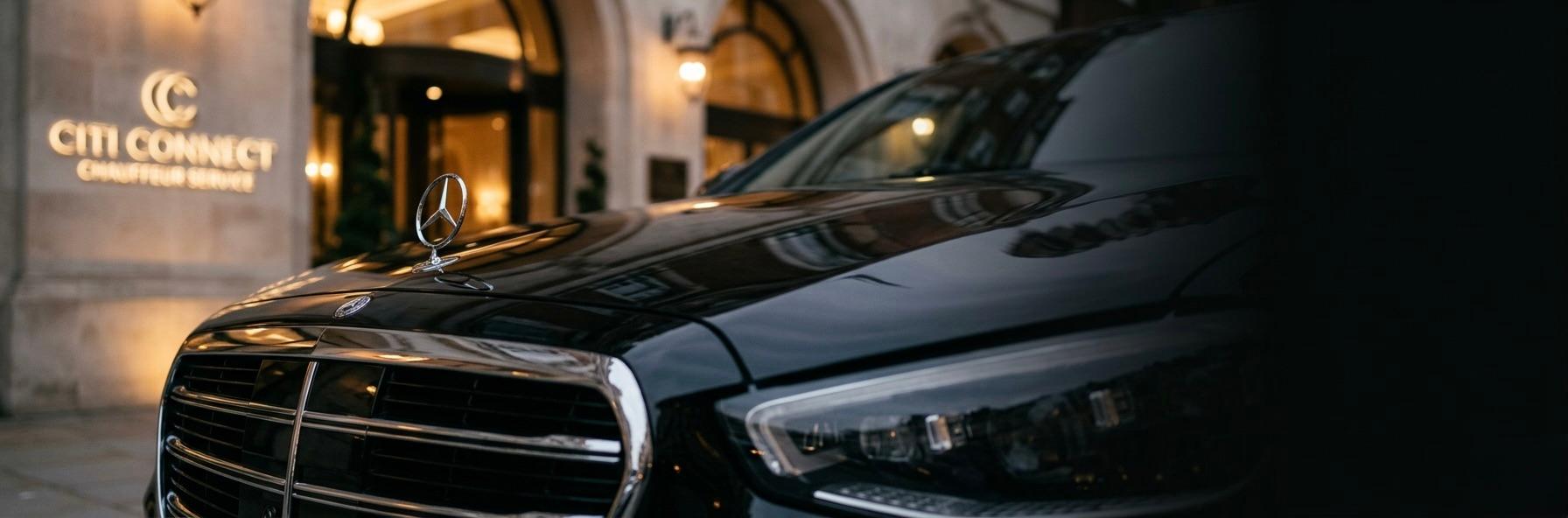 Chauffeur opening the door of a luxury black Mercedes for a passenger